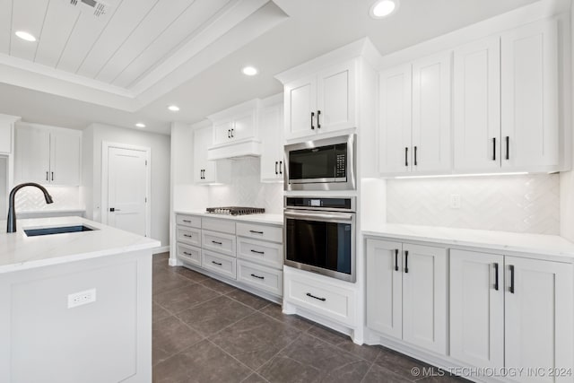 kitchen with appliances with stainless steel finishes, white cabinets, sink, and backsplash