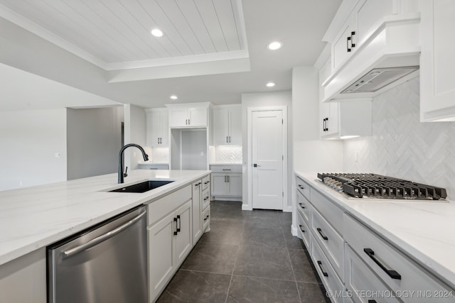 kitchen with stainless steel appliances, sink, light stone countertops, custom exhaust hood, and white cabinets