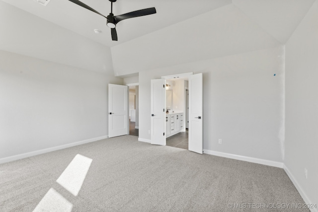 unfurnished bedroom with ensuite bathroom, carpet flooring, vaulted ceiling, and ceiling fan