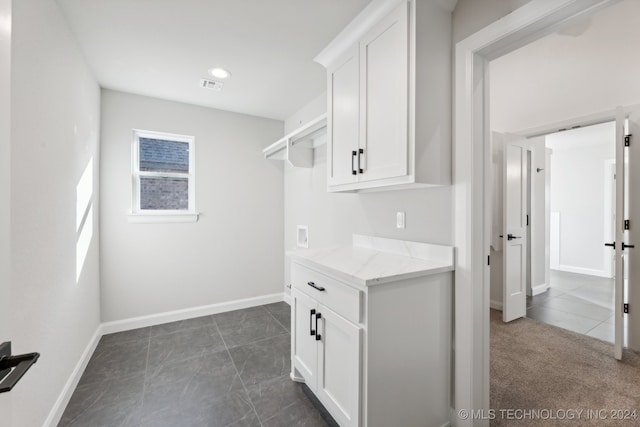 interior space featuring light stone counters and white cabinets