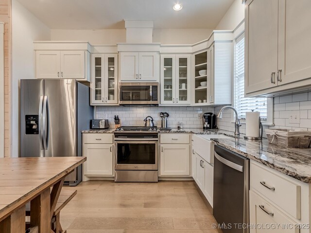 kitchen with white cabinets, light stone counters, and appliances with stainless steel finishes