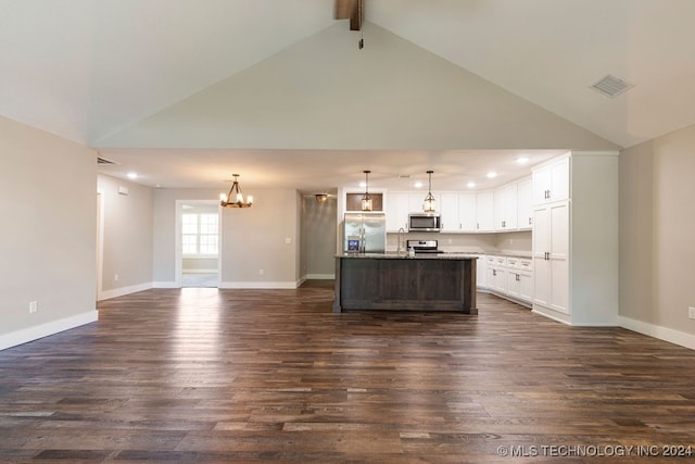 interior space with dark hardwood / wood-style floors, beamed ceiling, an island with sink, stainless steel appliances, and decorative light fixtures