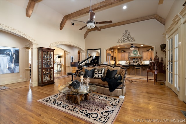 living room with light wood-type flooring, french doors, ornate columns, beamed ceiling, and high vaulted ceiling