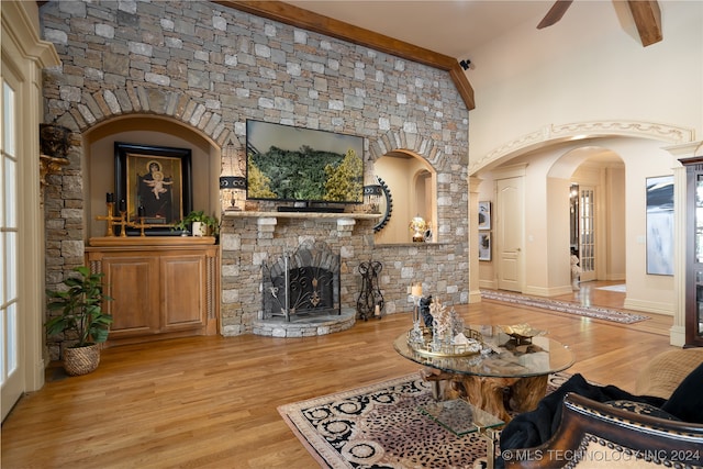 living room with beam ceiling, light wood-type flooring, a fireplace, high vaulted ceiling, and ceiling fan