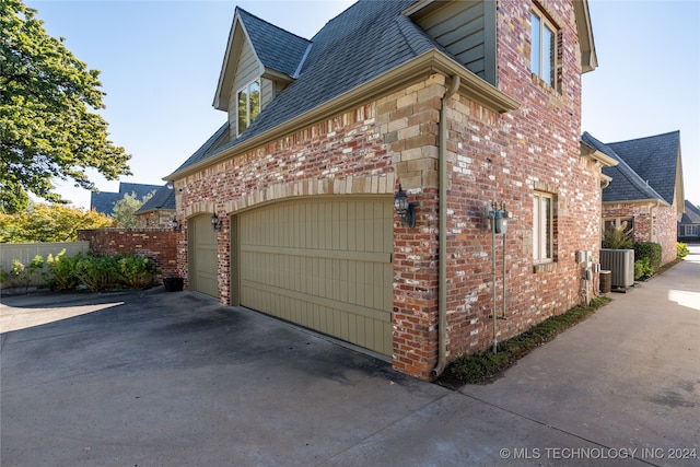 view of side of property featuring central AC unit and a garage