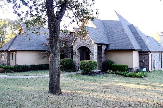 view of front facade with stone siding, brick siding, a front lawn, and stucco siding