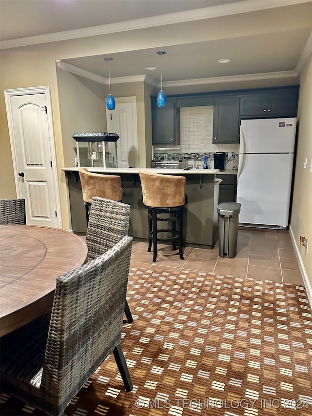 kitchen featuring light tile patterned floors, light countertops, decorative backsplash, ornamental molding, and freestanding refrigerator