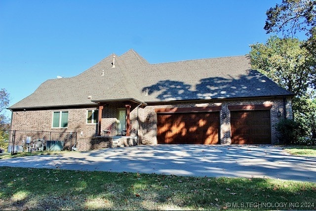 view of front of home featuring driveway, an attached garage, and brick siding