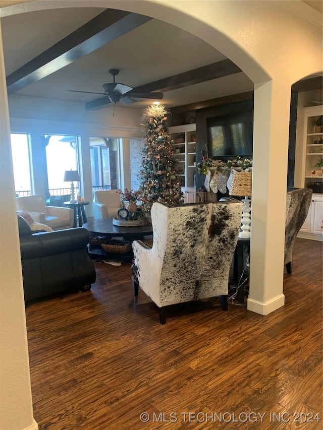 living area featuring ceiling fan, built in shelves, arched walkways, and wood finished floors