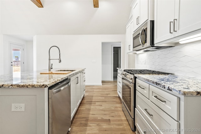 kitchen with light hardwood / wood-style flooring, stainless steel appliances, sink, light stone countertops, and white cabinets