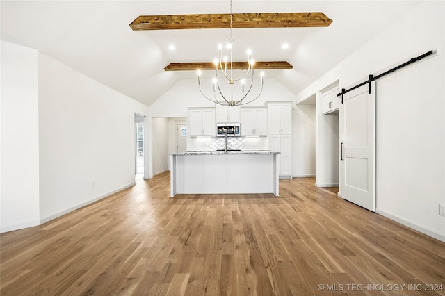 kitchen with an inviting chandelier, white cabinetry, a barn door, light stone countertops, and light hardwood / wood-style flooring