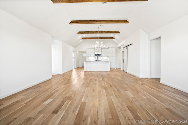 unfurnished living room featuring a notable chandelier, a barn door, light hardwood / wood-style flooring, and lofted ceiling with beams