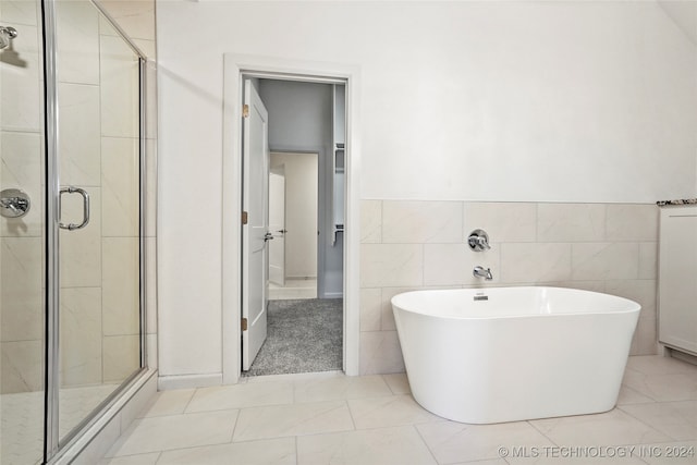 bathroom with tile walls, separate shower and tub, and tile patterned flooring