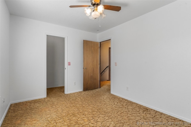 unfurnished bedroom featuring carpet, a walk in closet, a ceiling fan, and baseboards