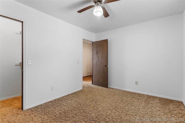 carpeted empty room with ceiling fan and baseboards