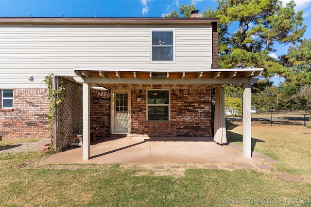 rear view of property with a patio, brick siding, a lawn, and a chimney