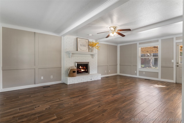 unfurnished living room with ornamental molding, dark wood-style flooring, a textured ceiling, a fireplace, and a decorative wall