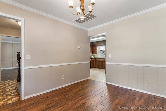 spare room with wainscoting, visible vents, a notable chandelier, and wood finished floors