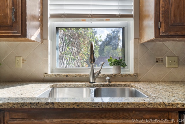 kitchen featuring light stone counters, a sink, and decorative backsplash