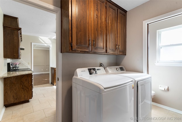 washroom with cabinet space, light tile patterned floors, baseboards, and washer and clothes dryer