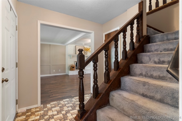 stairway featuring a textured ceiling and baseboards