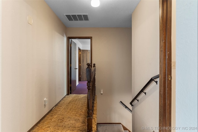 hall with light colored carpet, visible vents, and an upstairs landing