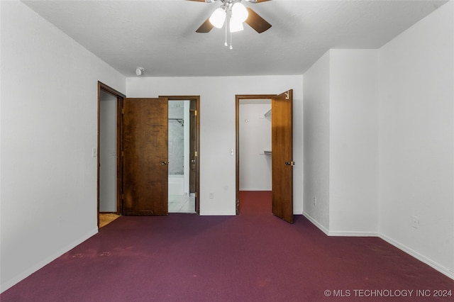 unfurnished bedroom with baseboards, a ceiling fan, ensuite bath, carpet, and a spacious closet