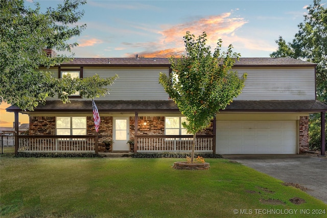 multi unit property featuring brick siding, a porch, an attached garage, a front yard, and driveway