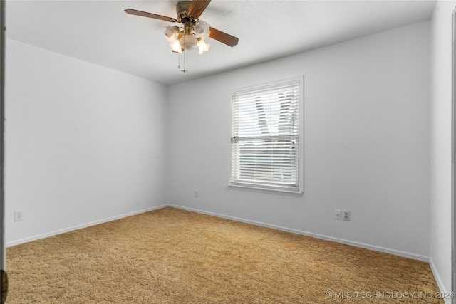 carpeted spare room with a ceiling fan and baseboards