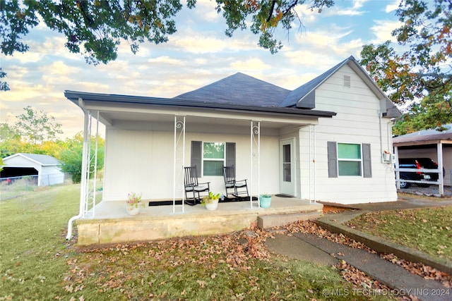 back of property featuring a porch, a lawn, and a carport