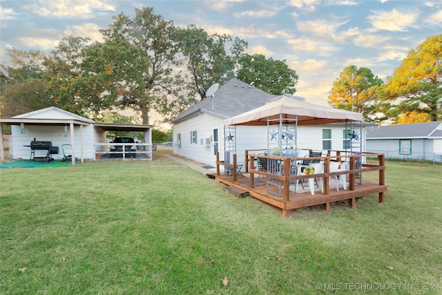 back house at dusk featuring a deck and a lawn