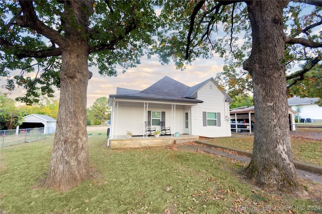 view of front of property featuring a porch, a yard, and a carport