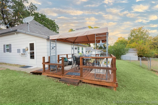 back house at dusk featuring a deck and a yard