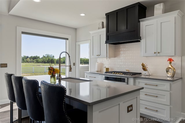 kitchen featuring sink, white cabinetry, stainless steel appliances, dark wood-type flooring, and a center island with sink