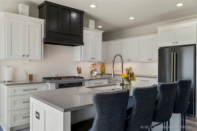 kitchen featuring dark hardwood / wood-style flooring, a breakfast bar, white cabinetry, a kitchen island with sink, and sink