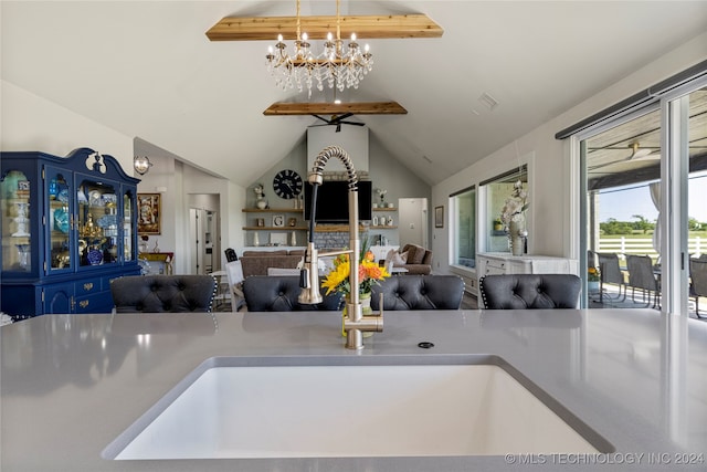 kitchen with blue cabinetry, lofted ceiling with beams, sink, and pendant lighting