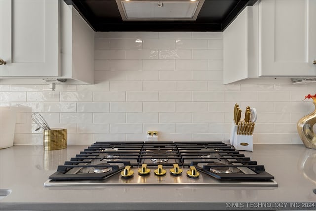 interior details featuring white cabinetry, stainless steel gas cooktop, extractor fan, and decorative backsplash