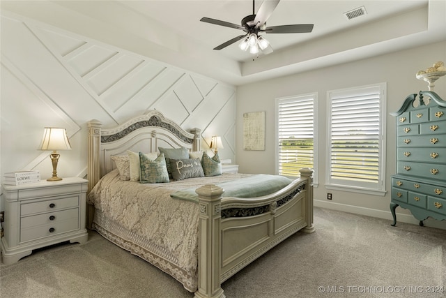 carpeted bedroom with a tray ceiling and ceiling fan