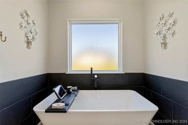 bathroom featuring tile walls and a washtub