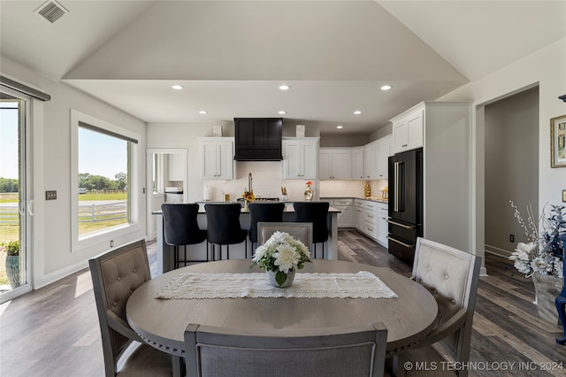 dining space featuring dark wood-type flooring and vaulted ceiling