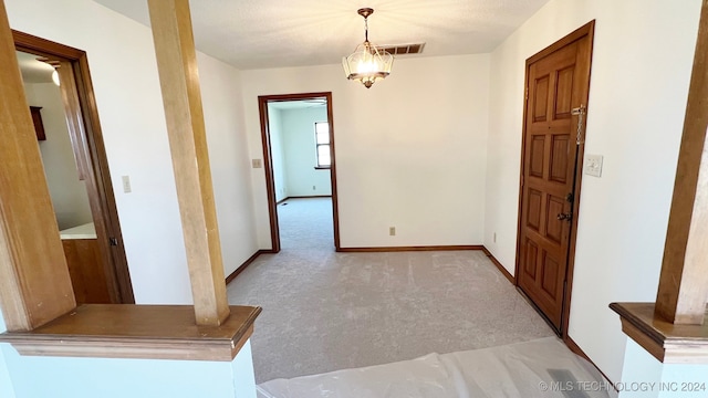 hallway with light carpet and a chandelier