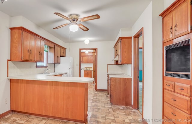 kitchen with sink, ceiling fan, white fridge, and kitchen peninsula