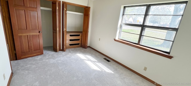 unfurnished bedroom featuring a closet and light colored carpet