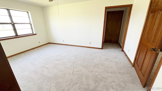 empty room featuring light colored carpet and ceiling fan