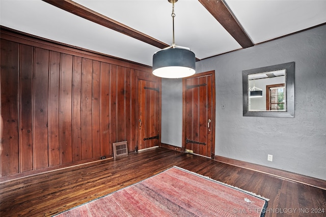 spare room featuring beam ceiling, dark hardwood / wood-style flooring, and wood walls