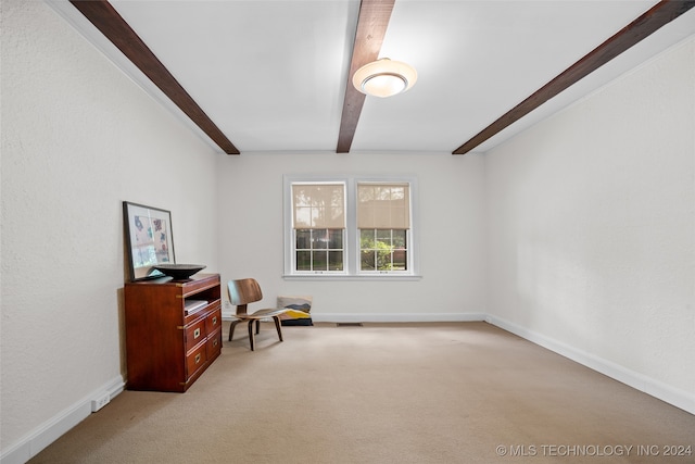 living area with beamed ceiling and light colored carpet