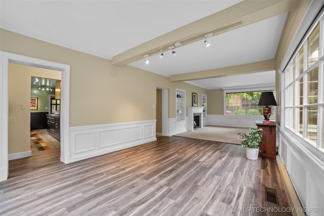 unfurnished living room featuring crown molding, track lighting, and hardwood / wood-style floors