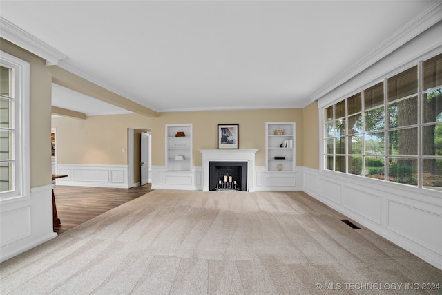 unfurnished living room with ornamental molding, carpet flooring, and built in shelves