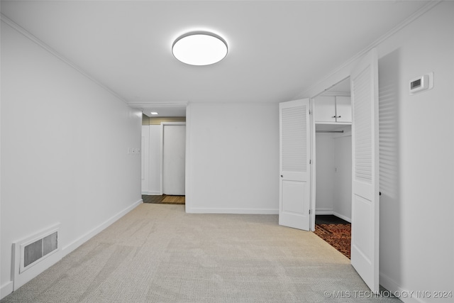 unfurnished bedroom with crown molding, light colored carpet, and a closet