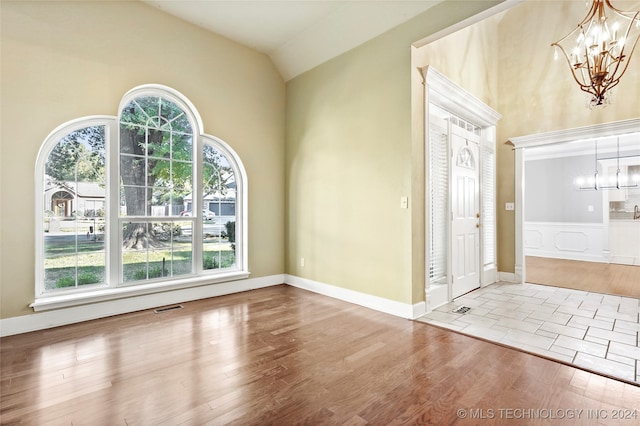 foyer entrance featuring a notable chandelier, hardwood / wood-style flooring, vaulted ceiling, and plenty of natural light